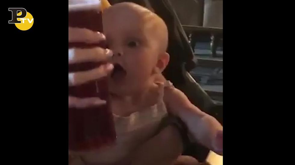Bambino cerca di rubare la birra alla mamma
