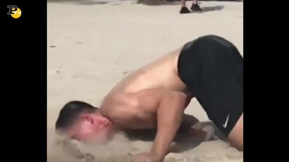 Ragazzo tenta di fare un'acrobazia sulla sabbia ma cade di faccia