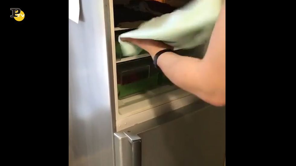 Ragazzo tiene la t-shirt nel frigorifero per combattere il caldo