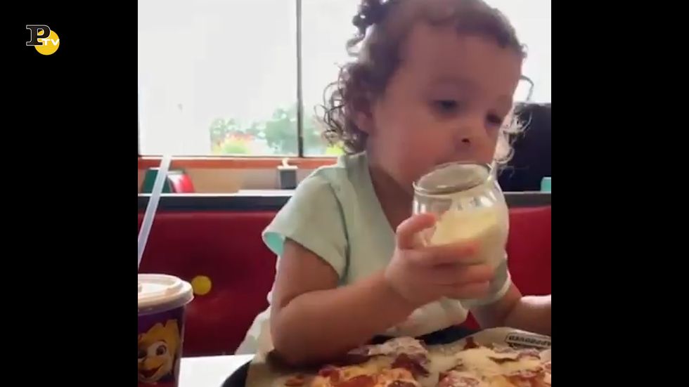 Una bambina affamata vuole tanto formaggio sulla pizza