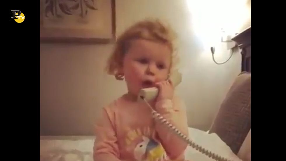 Una simpatica bambina parla al telefono con un amico immaginario