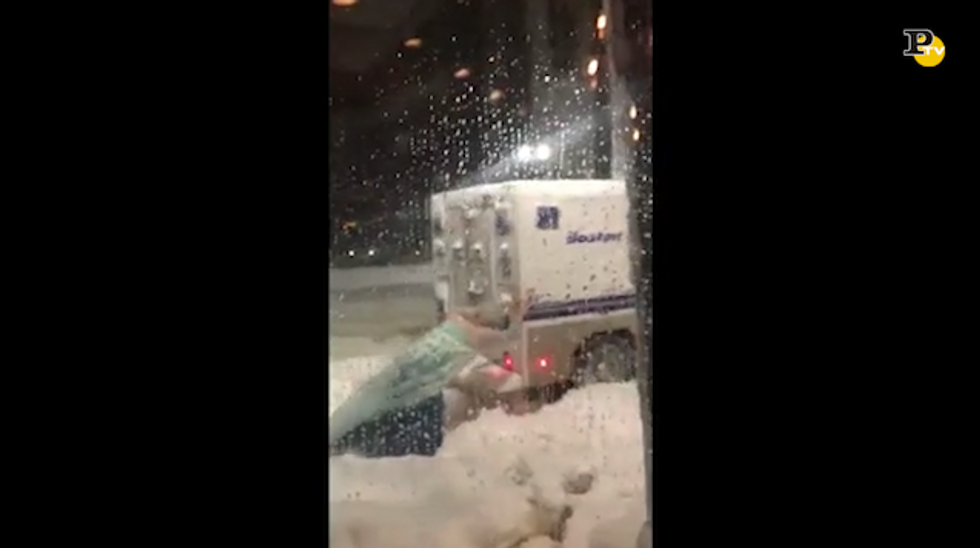 Uomo vestito da Elsa spinge il camioncino della polizia bloccato nella neve