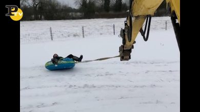 Uomo si diverte su un canotto attaccato ad una ruspa
