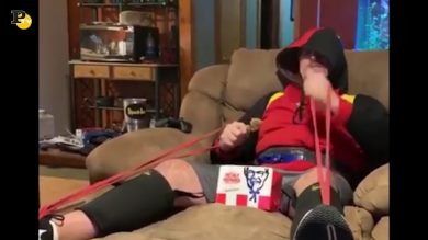 Uomo fa palestra mangiando sul divano