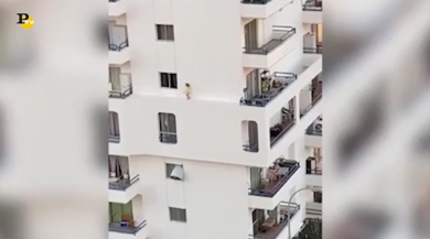 La bimba cammina sul cornicione di un palazzo in Spagna