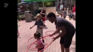 La bimba è troppo piccola per giocare con l’hula hoop, ma il papà la aiuta