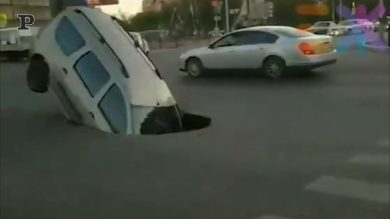 Una voragine si apre nel cemento e un’auto ci finisce dentro | video