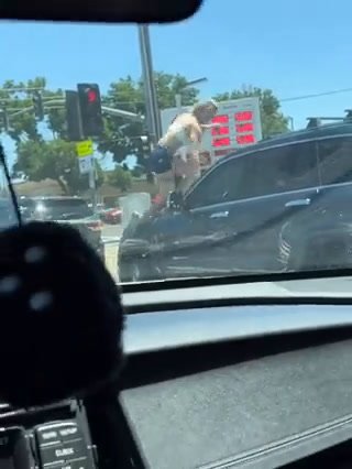 Sale sul cofano di una macchina e sfonda il vetro a calci | video